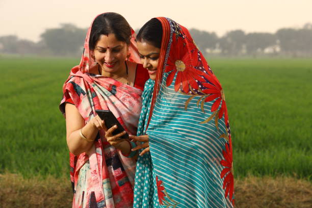 Rural women using phone in villlage Indian Rural farmer women using phone in the field and learning technology. developing countries photos stock pictures, royalty-free photos & images