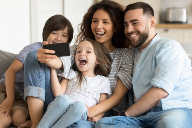 istock Overjoyed parents with two adorable kids posing for selfie together 1309085614