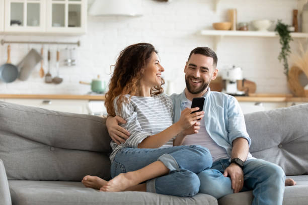 istock Happy young couple using smartphone together, relaxing on couch 1309085634