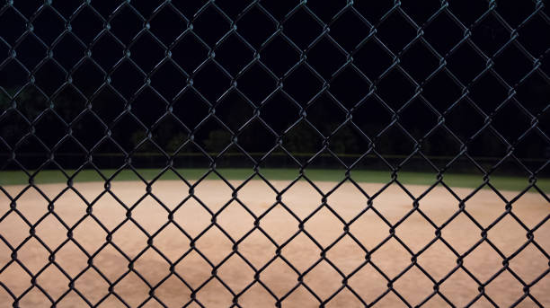 istock Looking through a fence at a baseball field at night. 1309086579
