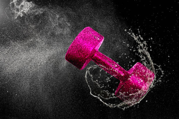 Dumbbell flying in water drops and splashes isolated on black background
