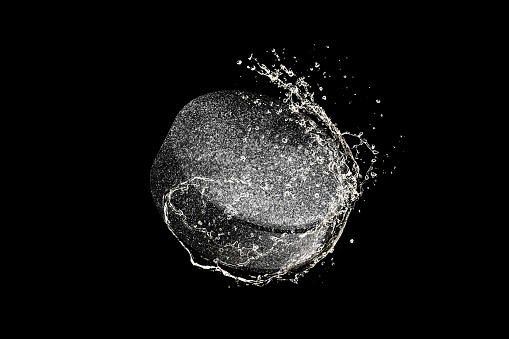 Hockey puck flying in macro water drops and splashes isolated on black background. Concept of motion, action in sport, competition, speed of game. Copyspace for ad. Highly detailed.