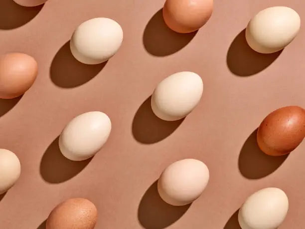 Photo of Egg pattern with hard shadow on brown background, from above