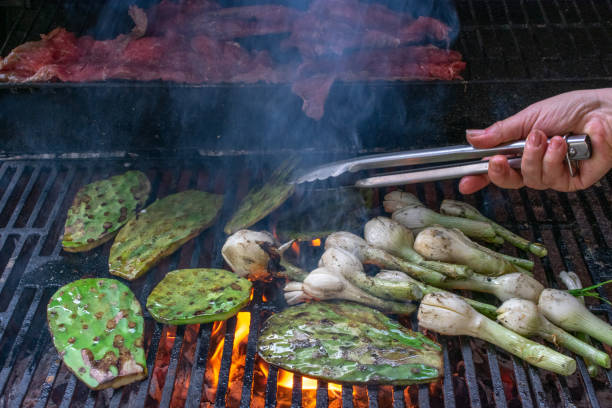 frontschuss eines grills, carne asada, nopales und holzkohle gegrillte kambray zwiebeln, während eine hand kocht sie. - prepared tuna stock-fotos und bilder