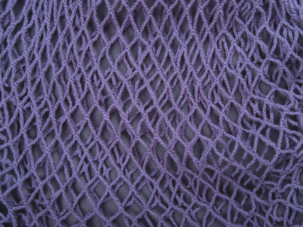 The knitted net background of one blue zero waste string bag, closeup. Selective focus.