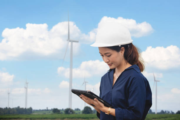 ingénieur féminin utilisant la tablette pour travailler sur le site à la ferme d’éolienne - engineer wind turbine alternative energy energy photos et images de collection