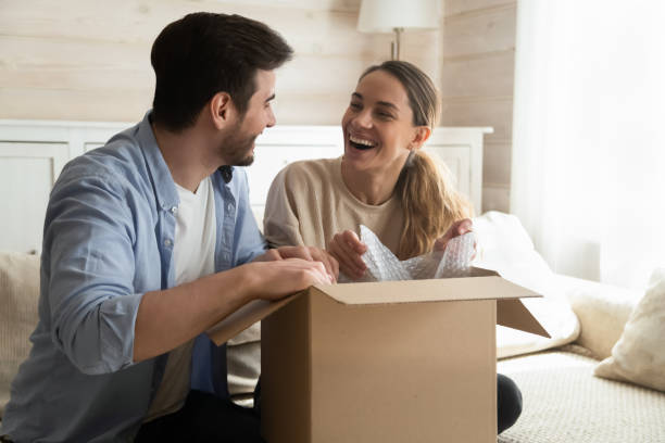 istock Overjoyed laughing millennial husband and wife unboxing packages after relocation 1309100973