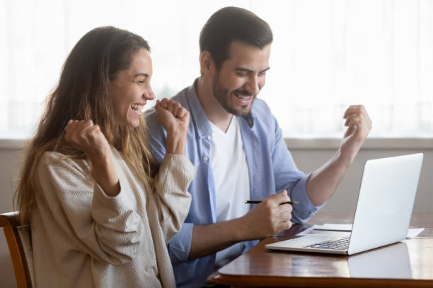 istock Excited young couple sitting by pc screen receiving profitable offer 1309101012