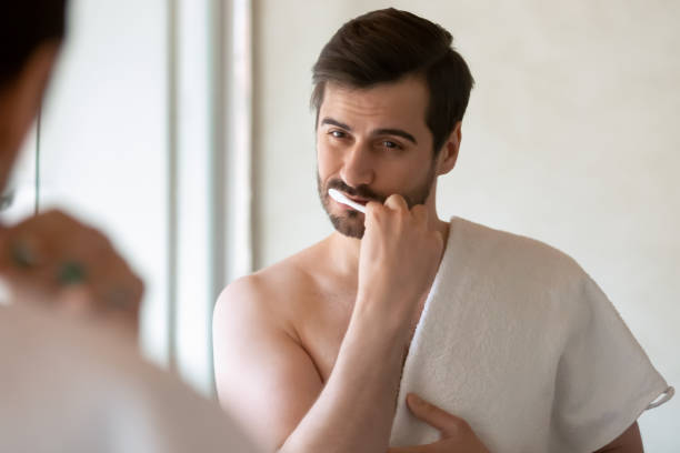 istock Handsome young man brushing teeth holding towel on shoulder 1309101028