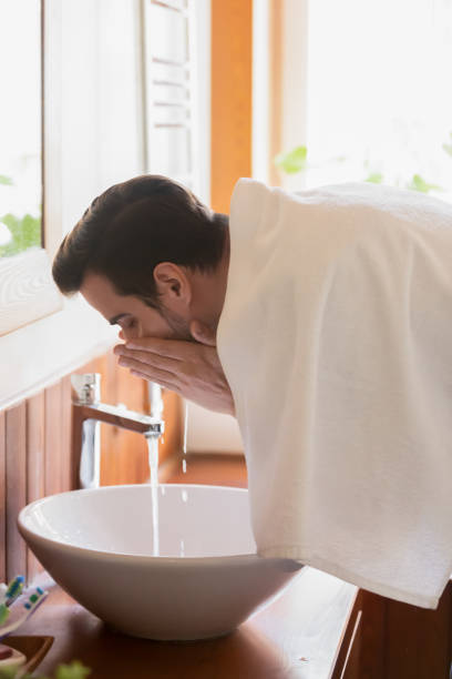istock Millennial man washing face in modern wash basin after shaving 1309101032