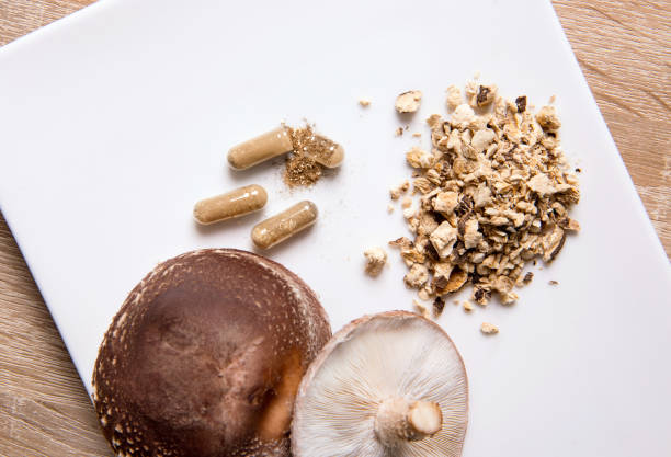 istock Shiitake Lentinus edoides mushroom supplement capsules with fresh Shiitake mushrooms and powdered on white minimal background. Flat lay view. 1309107359