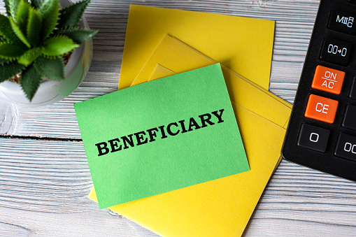 BENEFICIARY - words on green paper on the background of a calculator, and a cactus. Business concept