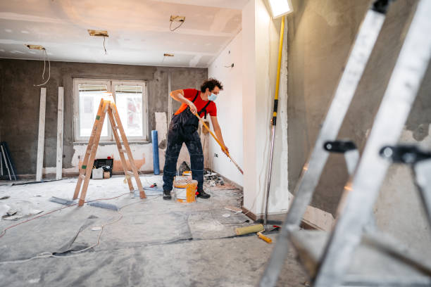 Man painting apartment walls Young man painting apartment walls and renovating apartment. He is wearing protective face mask. house painting service stock pictures, royalty-free photos & images
