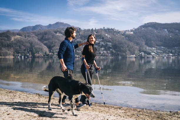 カップルは午前中に湖畔で彼らの犬と一緒に歩きます - ticino canton mountain lake lugano lake ストックフォトと画像