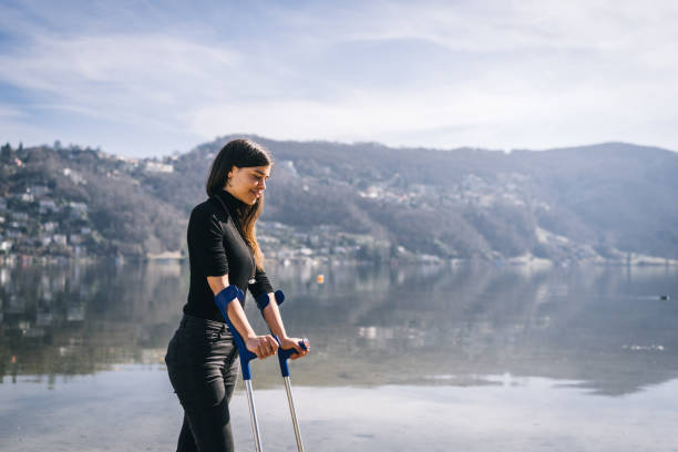 松葉杖を持つ若い女性は、午前中に湖畔を歩きます - ticino canton mountain lake lugano lake ストックフォトと画像