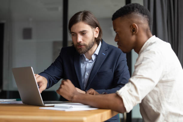 istock Concentrated two mixed race coworkers discussing presentation on laptop. 1309116004