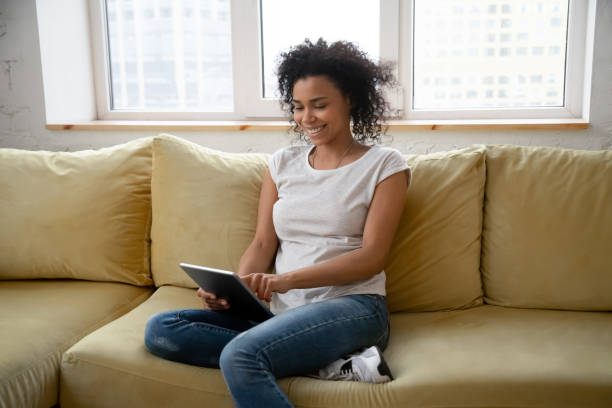 istock Happy smiling young african female using tablet computer at home 1309117528