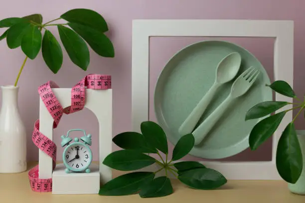 Photo of Creative composition with dishes, alarm clock, meter, decorative figures and leaves.