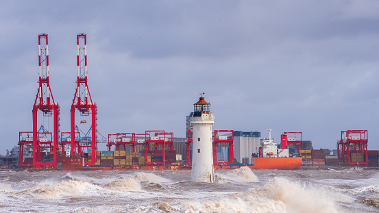 Perch rock lighthouse during a stormy day, large waves and industrial shipping.
