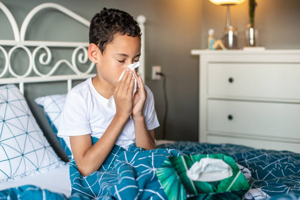 Young boy in bed, feeling sick Photo of a young boy having a cold respiratory disease stock pictures, royalty-free photos & images