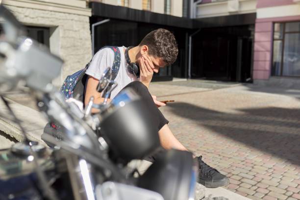 소년 십대 16,17 세, 스마트 폰을 사용하여, 여름 도시의 거리에 앉아 - 16 17 years audio 뉴스 사진 이미지