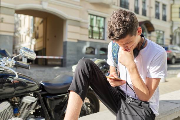 chłopiec nastolatek 16,17 lat, za pomocą smartfona, siedzący na ulicy letniego miasta - 18 19 years audio zdjęcia i obrazy z banku zdjęć