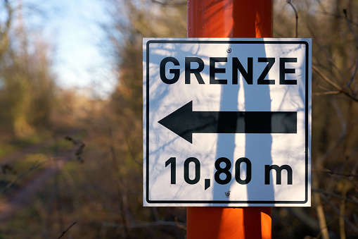 Sign with direction arrow and inscription border 10,80 meters at a forest road in Germany