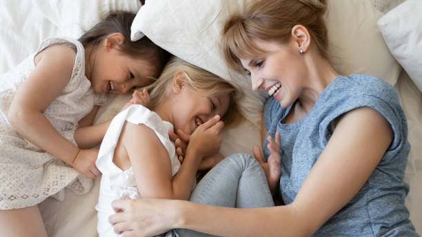 istock Top view overjoyed mother and two little daughters lying together 1309122588