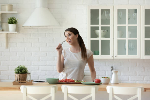 istock Funny young woman singing in spoon, standing in modern kitchen 1309122620