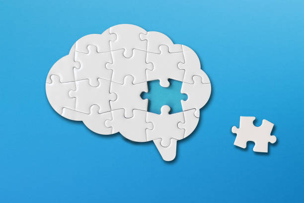 Brain shaped white jigsaw puzzle on blue background, a missing piece of the brain puzzle, mental health and problems with memory Brain shaped white jigsaw puzzle on blue background, a missing piece of the brain puzzle, mental health and problems with memory alzheimers disease photos stock pictures, royalty-free photos & images