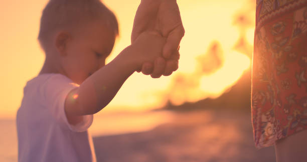 istock Mother and son holding hands at sunset. 1309122665