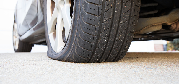 Close Up photo of a flat tire on a bright sunny day.