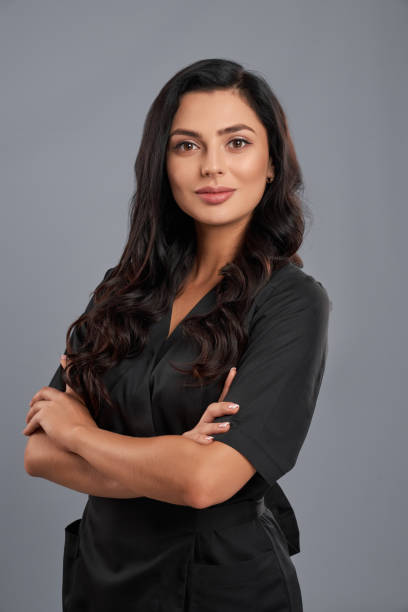 Adorable cosmetologist in black uniform posing indoors Adorable cosmetologist with clear skin wearing black medical uniform posing indoors. Isolated over grey studio background. Concept beauty procedures. beautician photos stock pictures, royalty-free photos & images