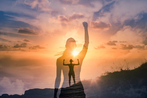 strong successful woman on a mountain flexing arms feeling inspired and motivated. - women standing fist success imagens e fotografias de stock