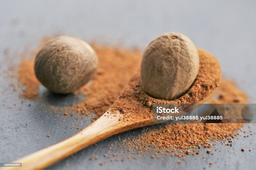 Nutmeg spice.Whole and ground nutmeg in a wooden spoon close-up on a black schiffer background.Spices and herbs.Food ingredient.Spices for meat and baking.Nutmeg powder Baking Stock Photo