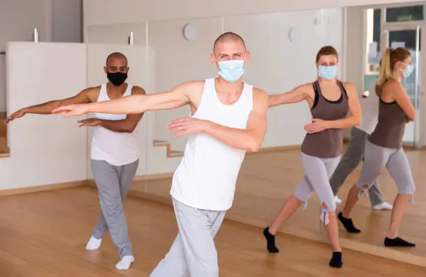 Photo of Man in mask dancing at group lesson