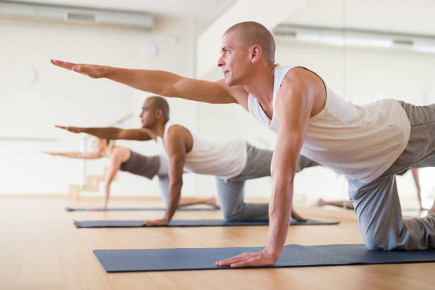 istock Man practicing Dandayamna Bharmanasana during group yoga training 1309124956