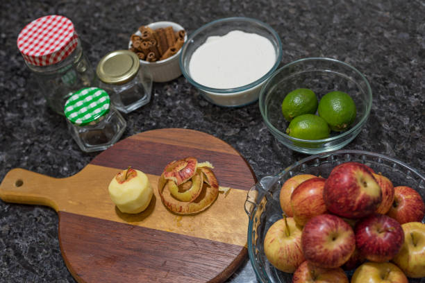Red apples in glass bowl, cinnamon sticks and utensils for making homemade jam