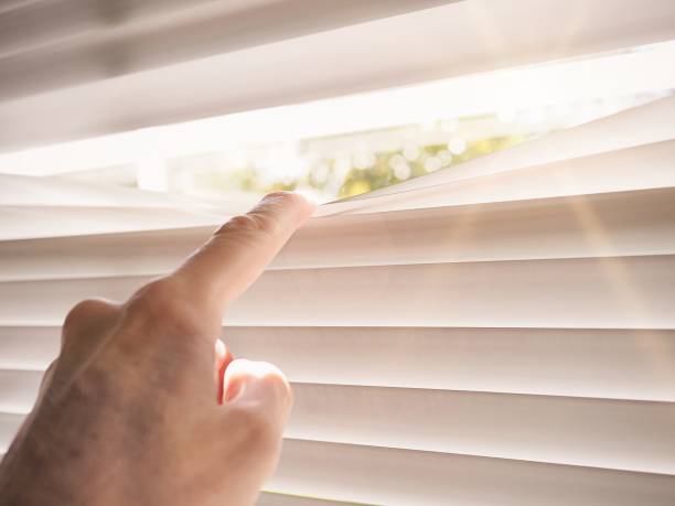 istock Hand peering through closed blinds, concept indicating aloneness isolation and fear 1309126251