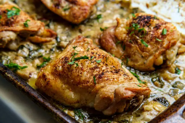 Crispy baked chicken thighs in a creamy spinach artichoke heart sauce