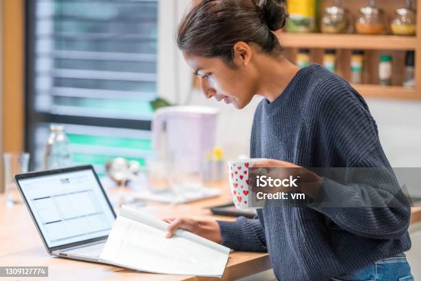 Woman Standing In Kitchen And Reading Brochure Stock Photo - Download Image Now - Home Office, Studying, Tea - Hot Drink