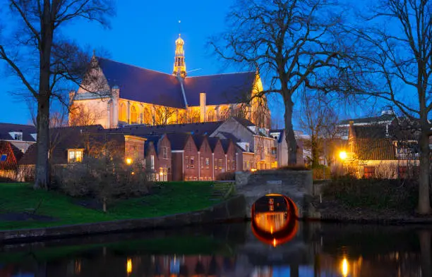 The big Saint-Laurens church in evening light in the historic city centre of Alkmaar, the Netherlands, with a canal, Singel, in the foreground. The small bridge is also a sluice.