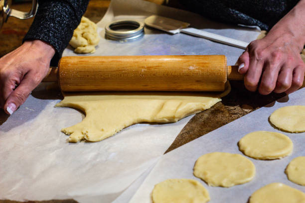 istock Woman hands rolling out sugar cookie dough with a rolling pin and cutting shapes. 1309129123