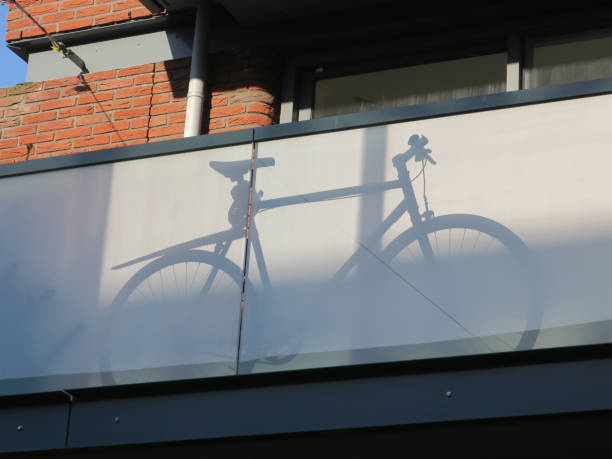 the shadow of a bicycle placed behind a glass balcony front