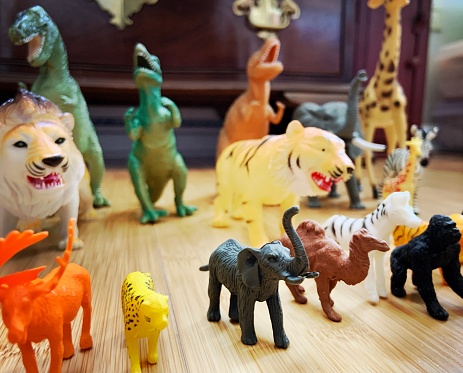 Smiling latin preschool kid boy having fun with dough, colorful modeling compound clay animals as a turtle, tiger and more in his bedroom studio.