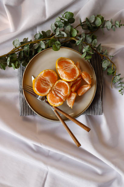 istock Tangerine slices on a gray plate on a white tablecloth, Close-up 1309136908