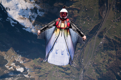 Wing suit soars above mountain landscape