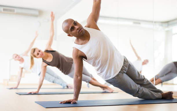 istock Latin american man practicing Vasisthasana during group yoga workout 1309140332