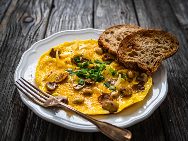 Continental breakfast -  scrambled eggs wuth white mushrooms and toasted bread on wooden table