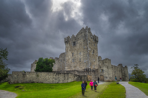 Killarney, Ireland, August 2019 People sightseeing and visiting beautiful, 15th century Ross Castle with dramatic storm sky and clouds, Ring of Kerry